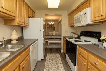 A kitchen with wooden cabinets and a white refrigerator.at Chapel Valley Townhomes, Maryland